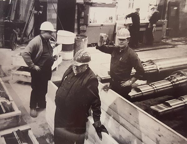 Circa 1974. Russ and Gene Eaborn with the Shipper determining how they are going to load and place a large rolling mill roll on the trailer.